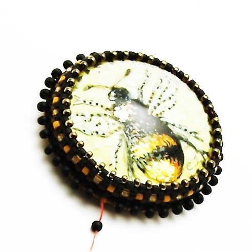 (10) Add the thread to the beadwork, and exit from the beaded backstitch one of the lower beads. Pick up one black color 11o rocaille and work one round in tubular, even-count peyote stitch around the beaded cab. pendant-tutorial-beaded-bezel