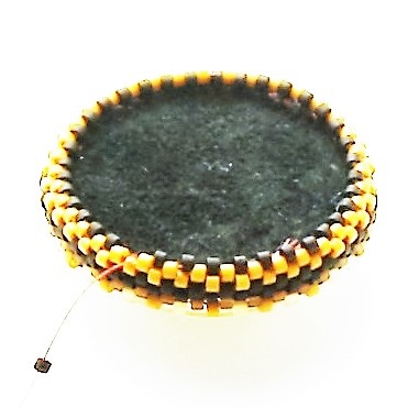 (8) Using sharps needle, sew back through the fabricks and the backstitched round one of the lower beads. Using the pumpkin color delica 11o Japanese seed beads continue adding rounds of peyote. seed-bead-tutorial